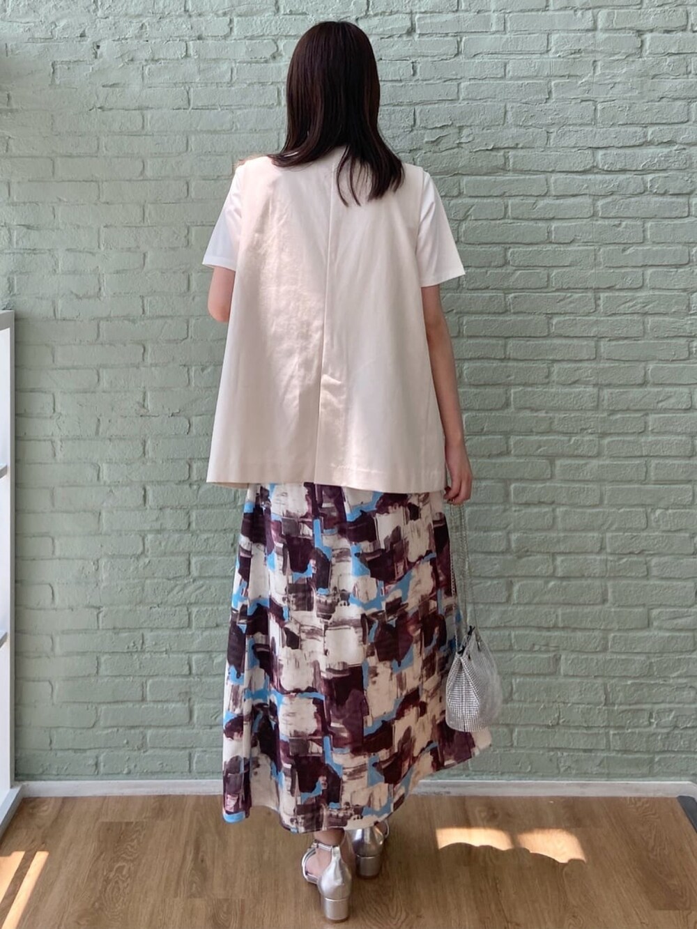 ベージュ系のベスト、ホワイト系のTシャツ/カットソー、レッド系のスカートを着用したレディースの夏コーディネートの5枚目の写真