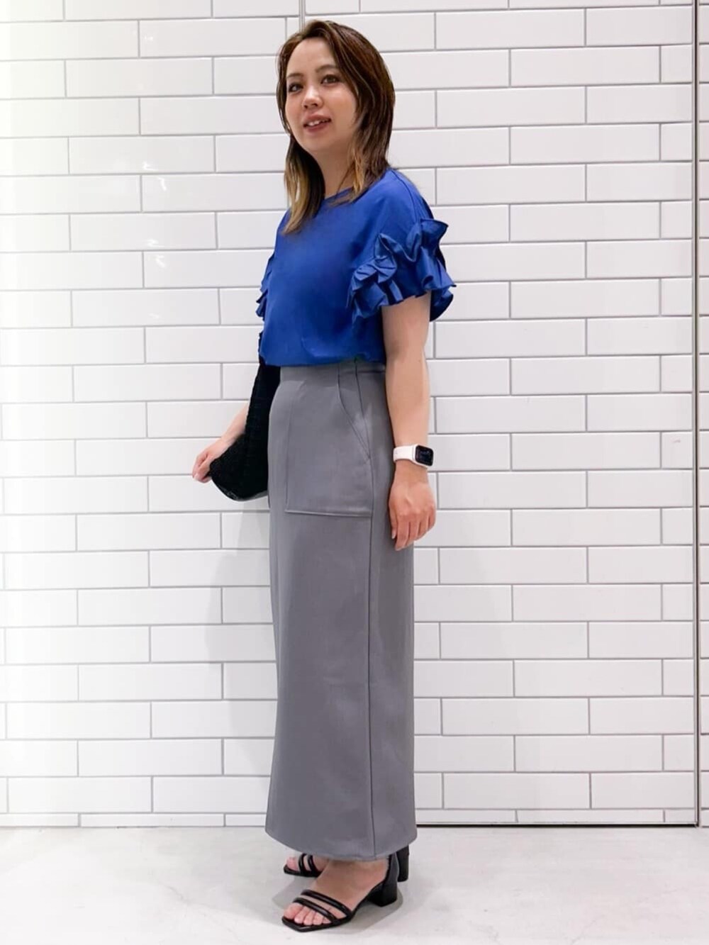 ブルー系のTシャツ/カットソー、ブラック系のサンダル、グレー系のスカートを着用したレディースの夏コーディネートの2枚目の写真