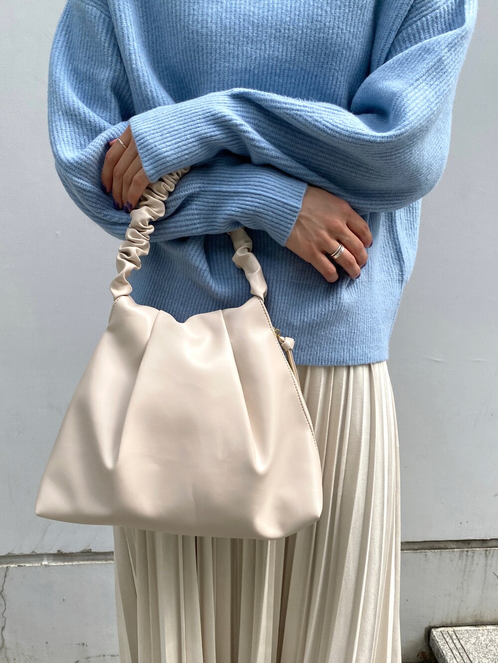 ブルー系のニット/セーター、ホワイト系のスカート、ホワイト系のハンドバッグを着用したレディースの秋コーディネートの4枚目の写真
