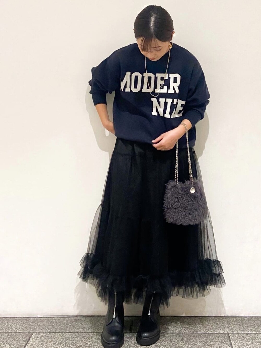 ブルー系のニット/セーター、ブラック系のスカート、グレー系のショルダーバッグを着用したレディースの冬コーディネートの2枚目の写真