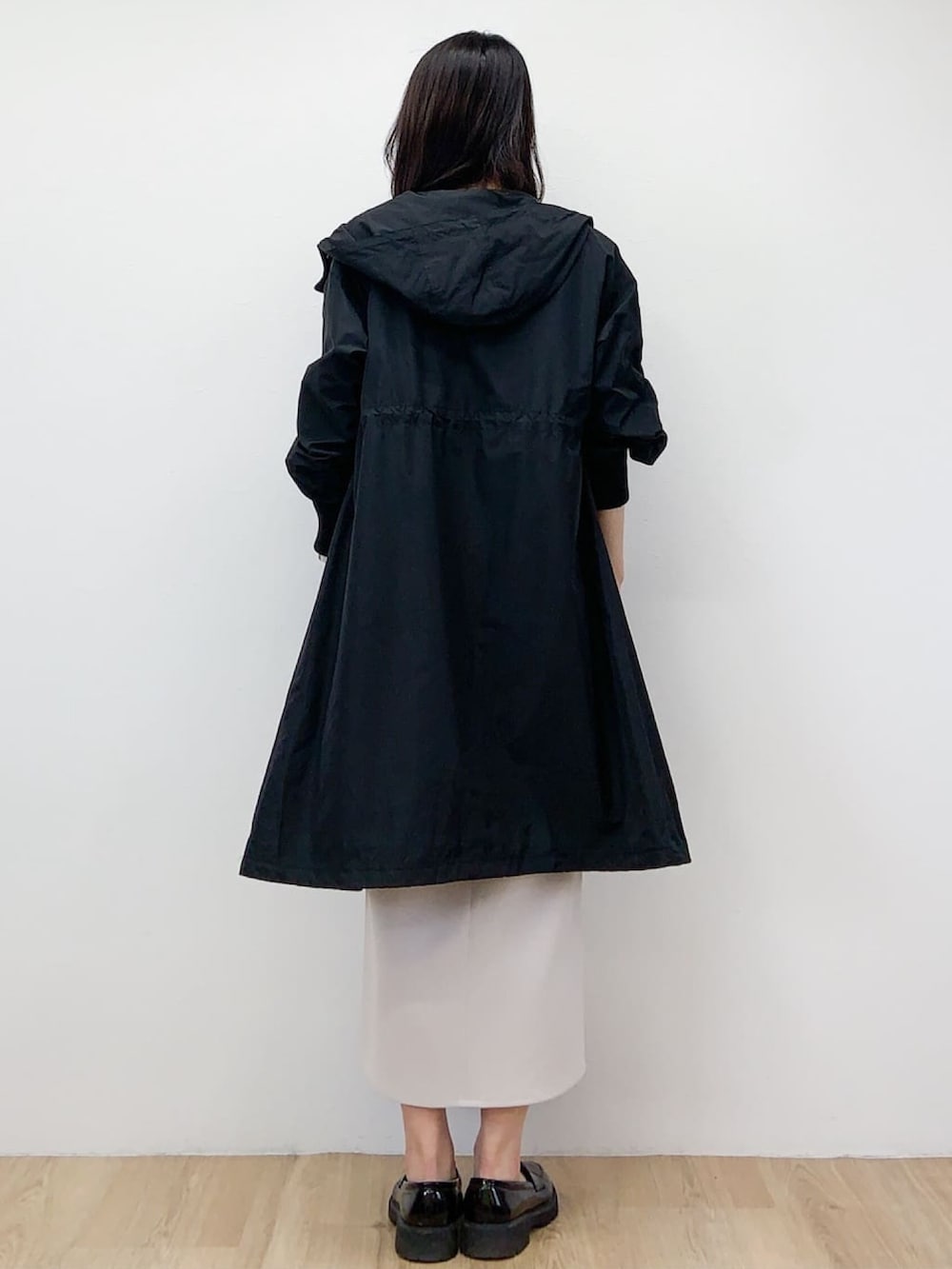 ブラック系のニット/セーター、ブラック系のその他アウター、ベージュ系のスカートを着用したレディースの春コーディネートの2枚目の写真