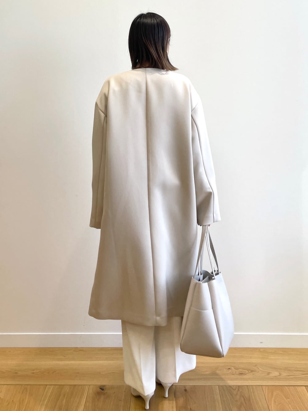 ホワイト系のノーカラーコート、ブルー系のニット/セーター、ホワイト系のその他パンツを着用したレディースの春コーディネートの3枚目の写真