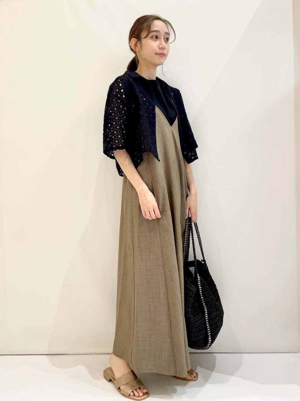 ベージュ系のワンピース、ブラック系のシャツ/ブラウス、ゴールド系のサンダルを着用したレディースの夏コーディネートの2枚目の写真