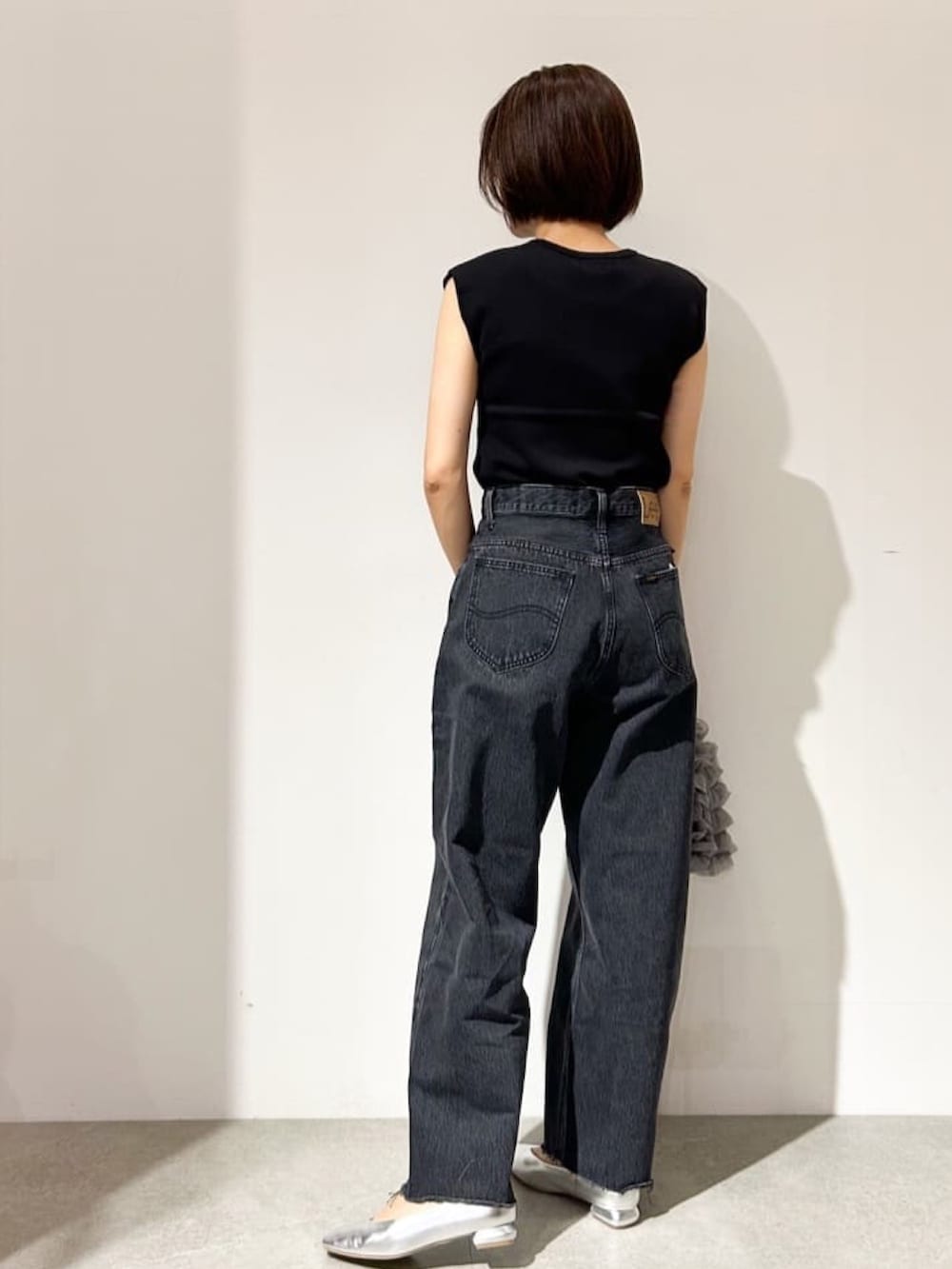 ブラック系のニット/セーター、グレー系のデニムパンツ、シルバー系のパンプスを着用したレディースの夏コーディネートの3枚目の写真
