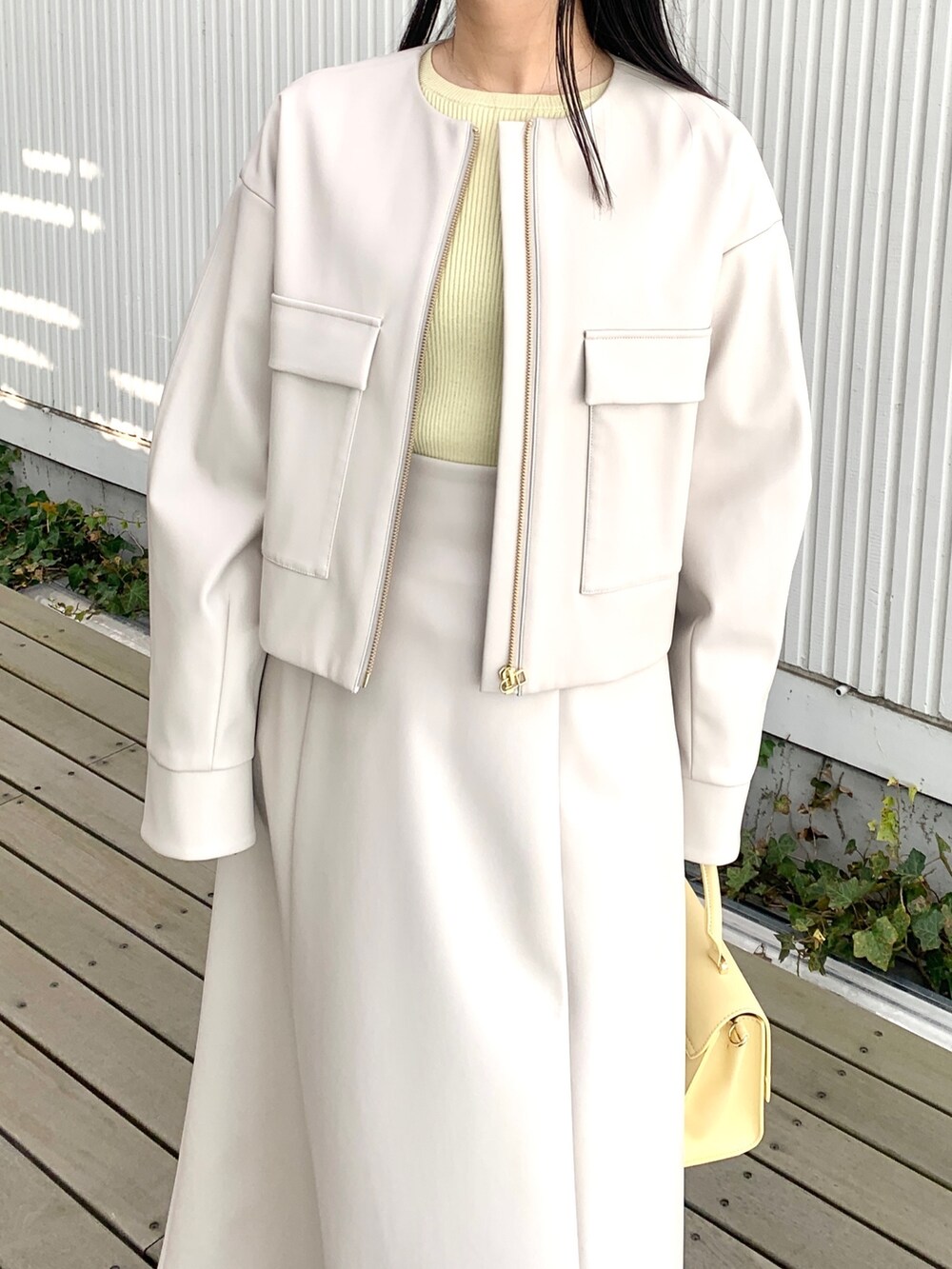 グレー系のブルゾン、イエロー系のニット/セーター、グレー系のスカートを着用したレディースの春コーディネートの3枚目の写真