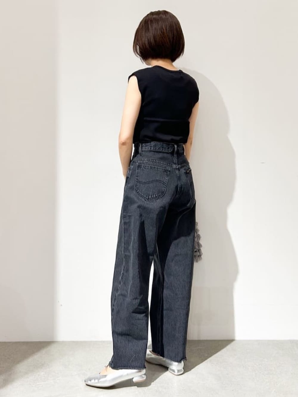 ブラック系のニット/セーター、グレー系のデニムパンツ、シルバー系のパンプスを着用したレディースの夏コーディネートの2枚目の写真