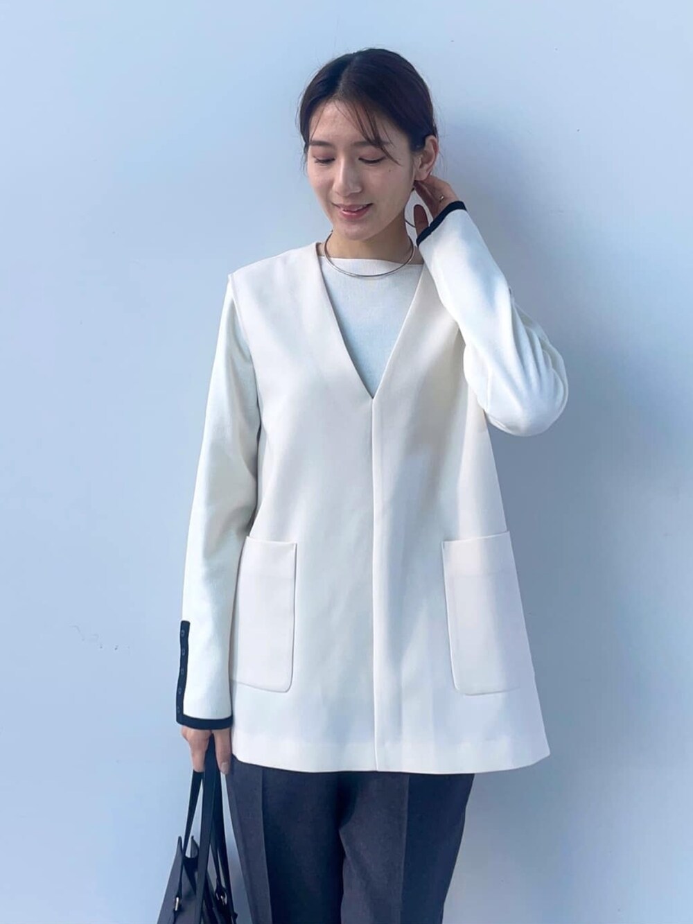 ホワイト系のニット/セーター、ホワイト系のベスト、ブラック系のトートバッグを着用したレディースの冬コーディネートの2枚目の写真