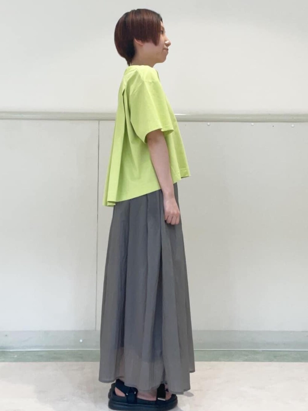 グレー系のスカート、ブラック系のサンダル、グリーン系のTシャツ/カットソーを着用したレディースの春コーディネートの5枚目の写真