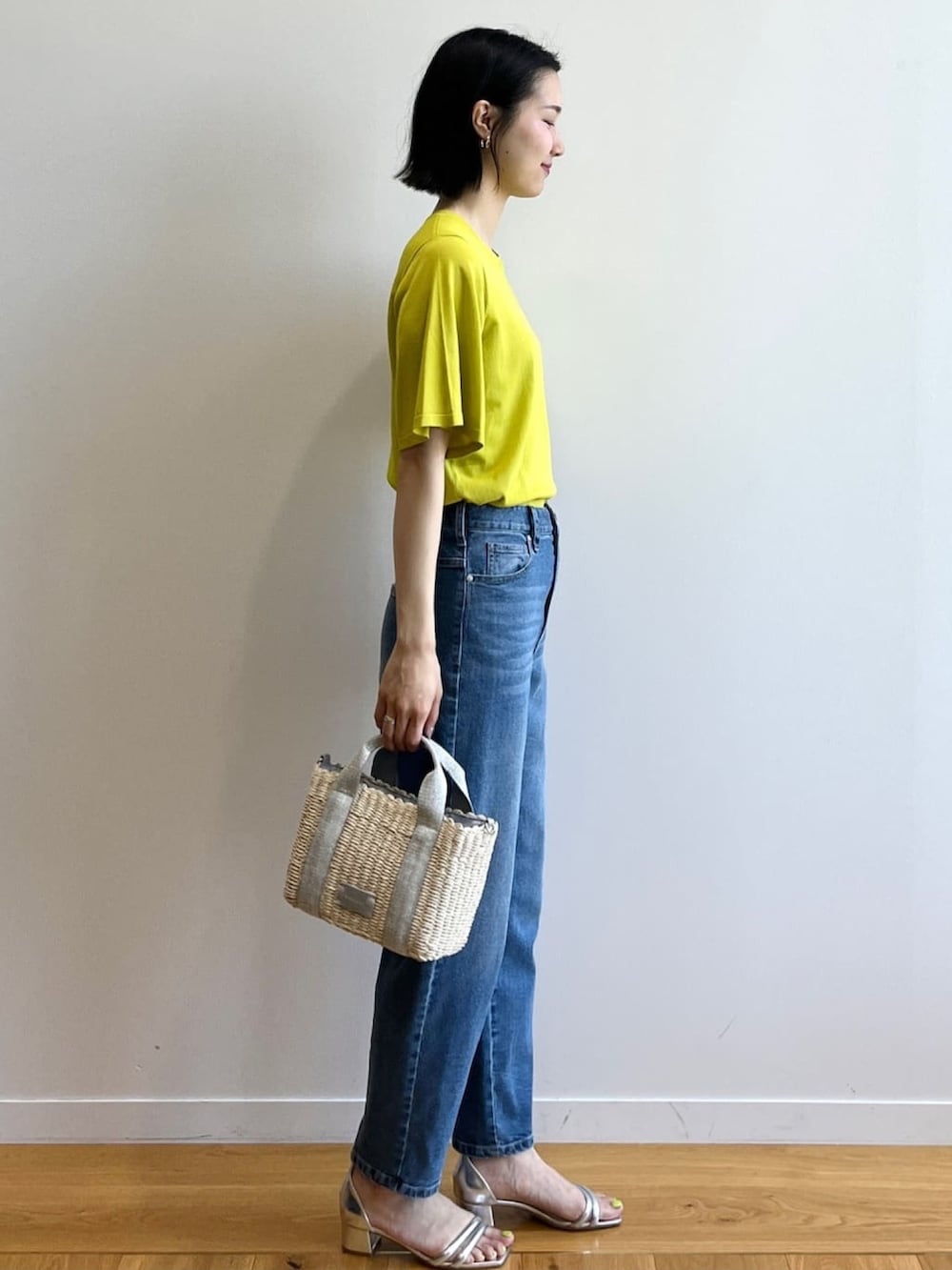 グリーン系のニット/セーター、ブルー系のデニムパンツ、シルバー系のショルダーバッグを着用したレディースの夏コーディネートの3枚目の写真