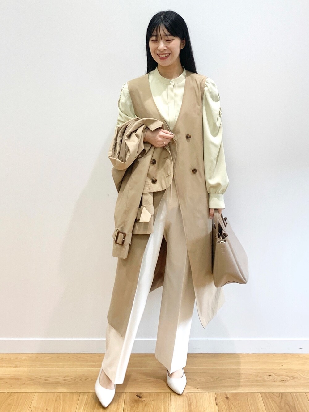 ベージュ系のトレンチコート、イエロー系のシャツ/ブラウス、ホワイト系のその他パンツを着用したレディースの春コーディネートの2枚目の写真