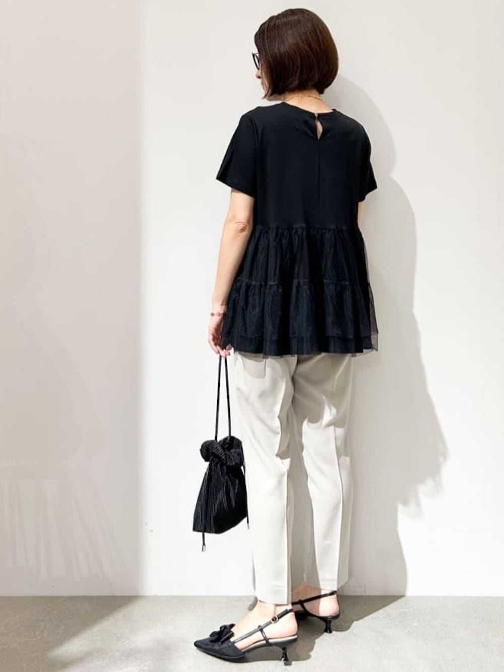 グレー系のその他パンツ、ブラック系のショルダーバッグ、ブラック系のパンプスを着用したレディースの春コーディネートの3枚目の写真