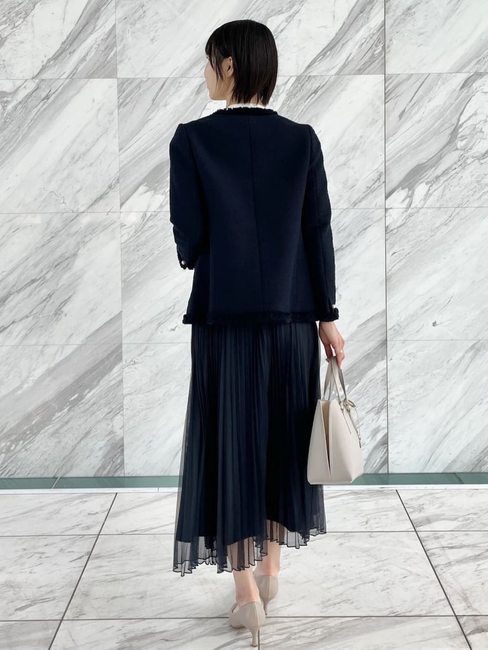 ブルー系のスカート、ホワイト系のシャツ/ブラウス、ブルー系のノーカラージャケットを着用したレディースの冬コーディネートの3枚目の写真