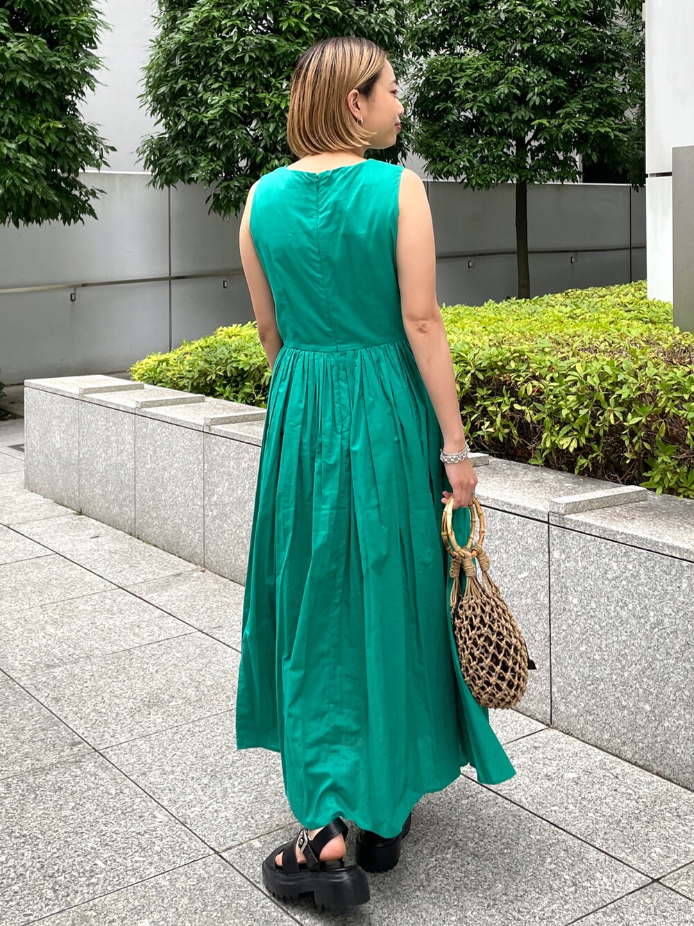 グリーン系のワンピース、ブラウン系のハンドバッグ、ブラック系のサンダルを着用したレディースの夏コーディネートの2枚目の写真