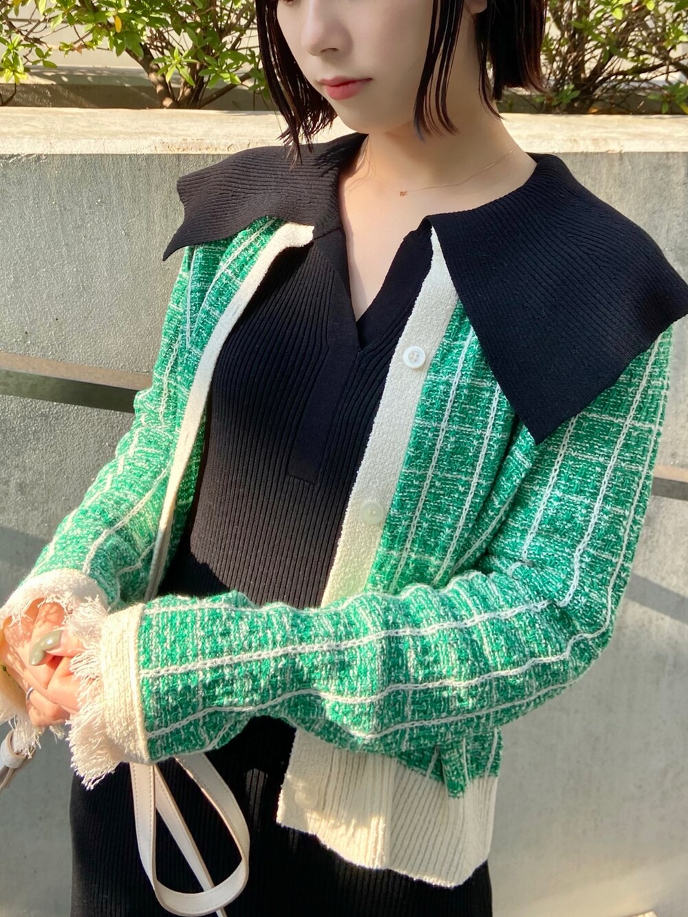 グリーン系のカーディガン/ボレロ、ブラック系のワンピース、ホワイト系のサンダルを着用したレディースの春コーディネートの3枚目の写真