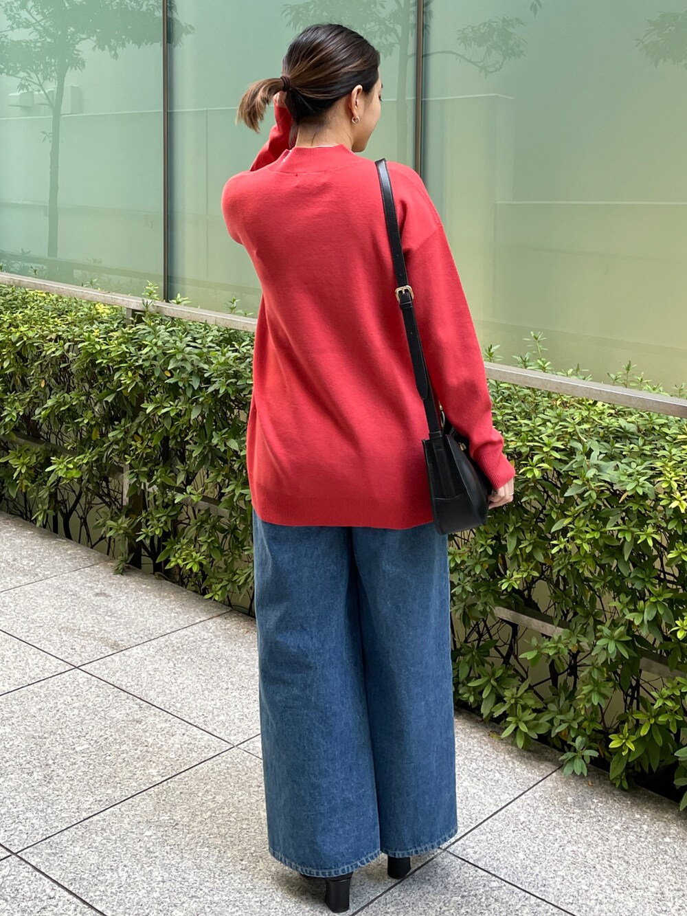 レッド系のニット/セーター、ブルー系のその他パンツ、ブラック系のブーツを着用したレディースの冬コーディネートの3枚目の写真