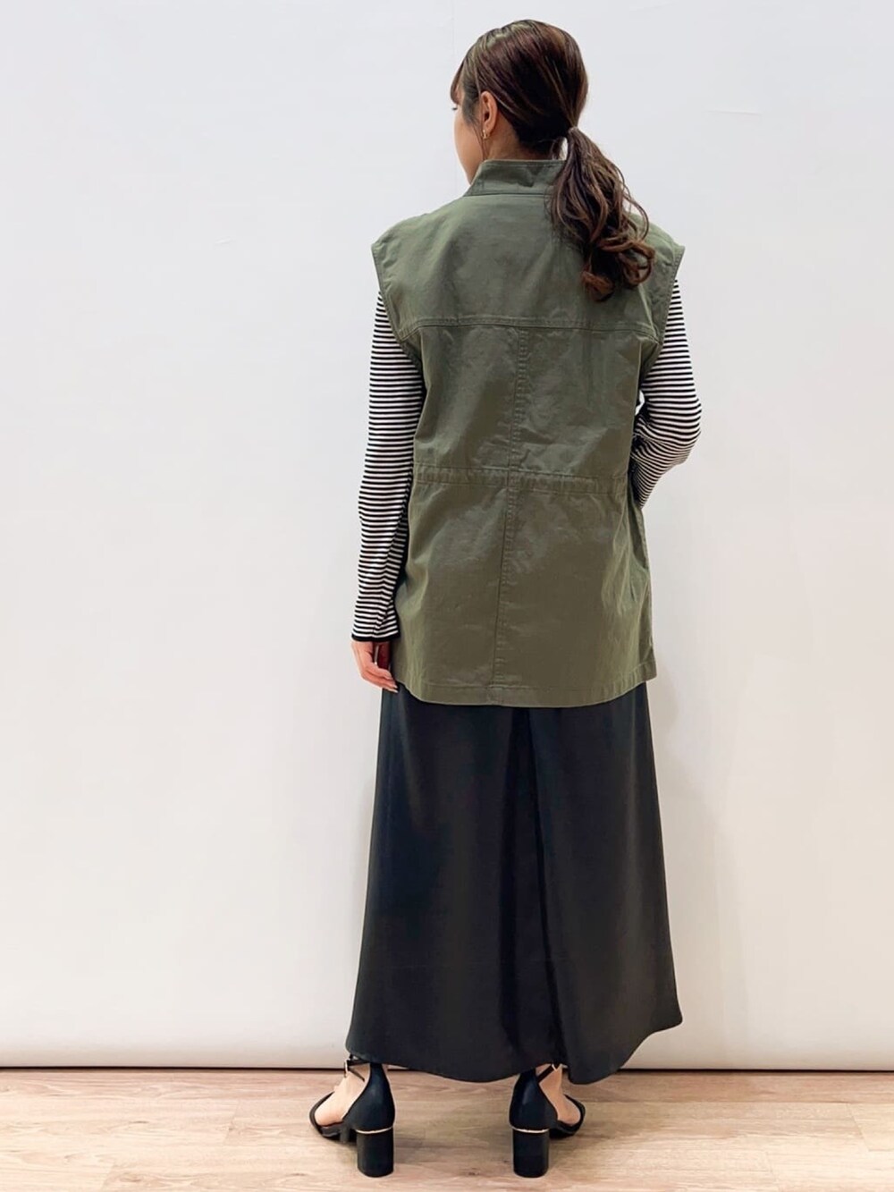 グレー系のワンピース、ブラック系のサンダル、ホワイト系のニット/セーターを着用したレディースの春コーディネートの3枚目の写真