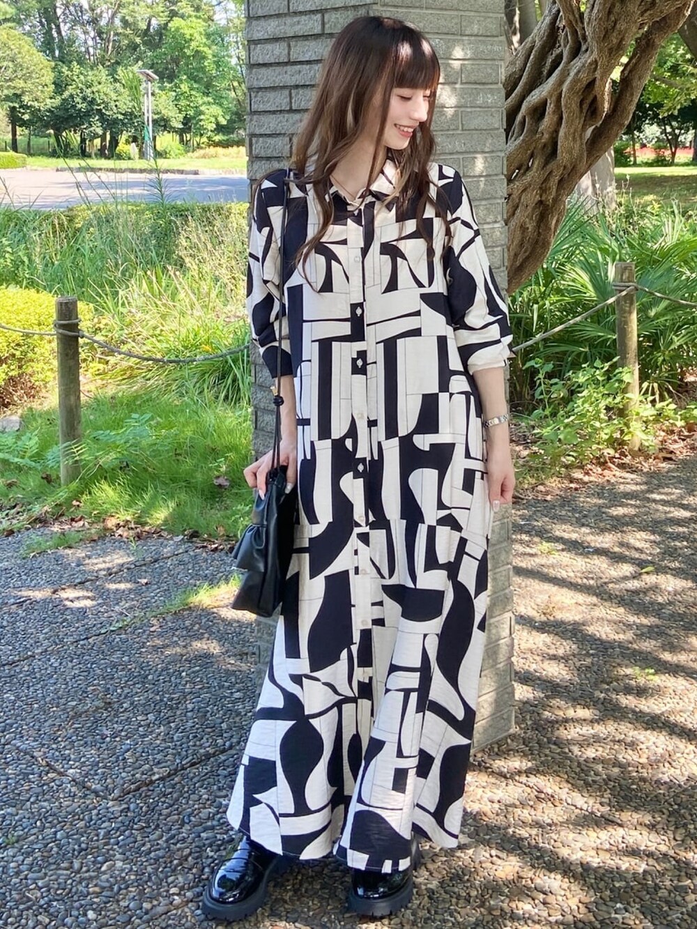 ベージュ系のワンピース、ブラック系のショルダーバッグを着用したレディースの秋コーディネートの2枚目の写真