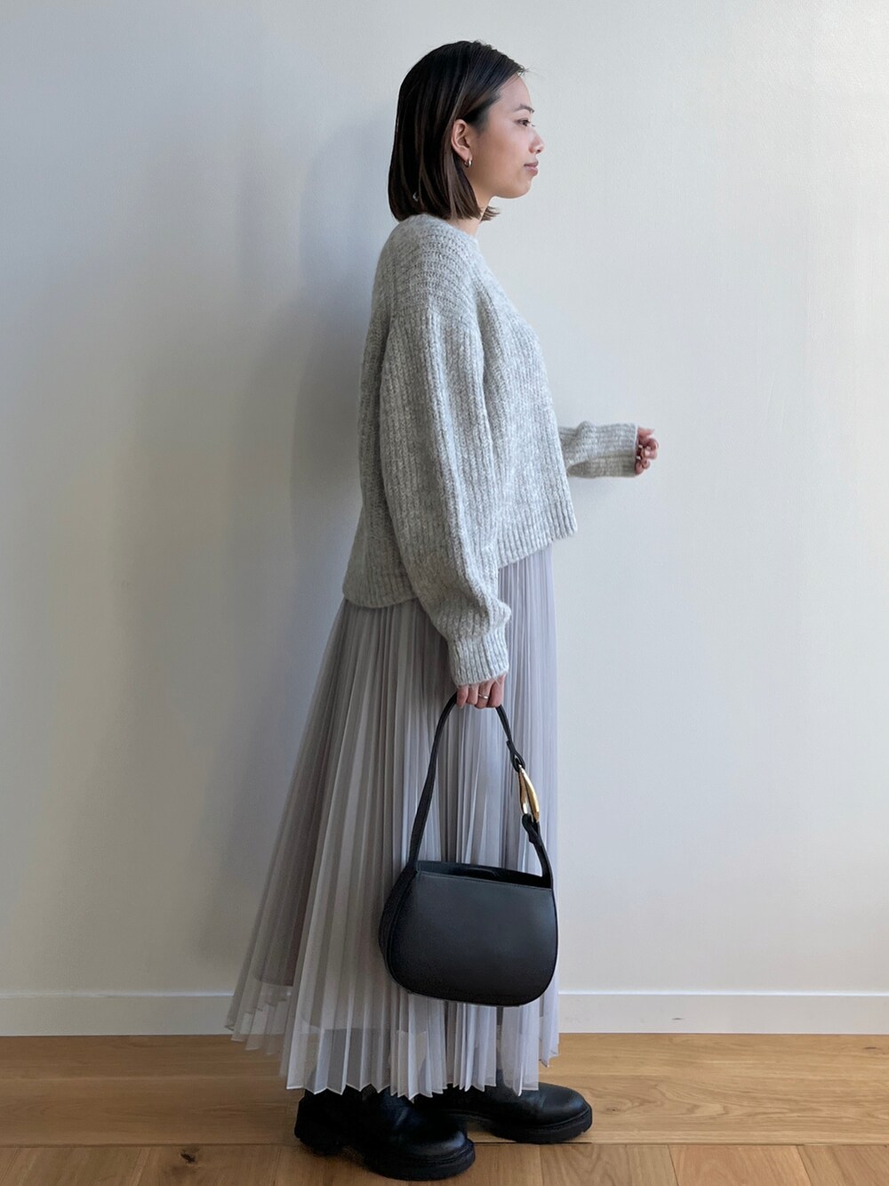 グレー系のニット/セーター、グレー系のスカート、ブラック系のブーツを着用したレディースの冬コーディネートの2枚目の写真