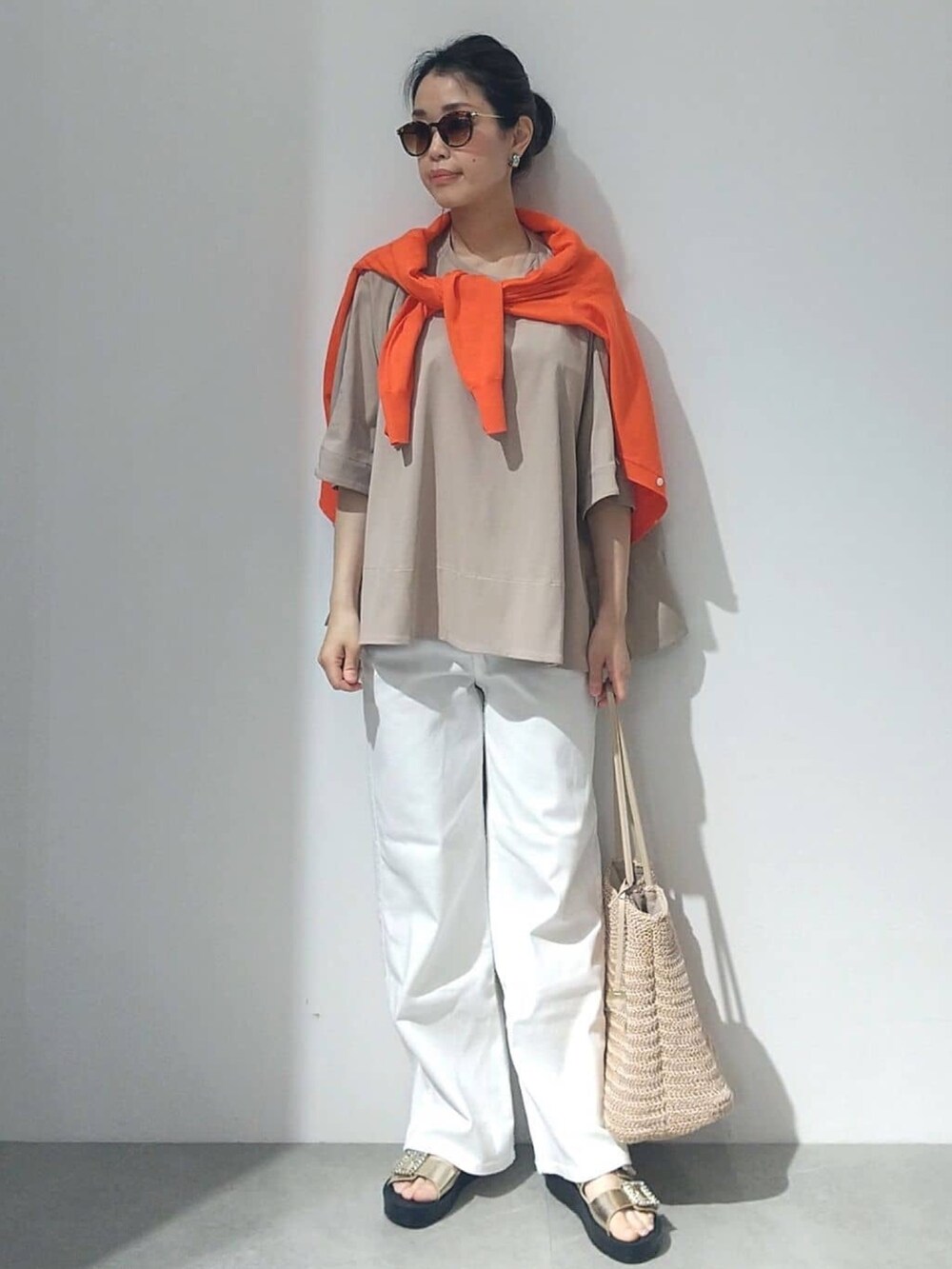 ベージュ系のTシャツ/カットソー、オレンジ系のカーディガン/ボレロ、ホワイト系のデニムパンツを着用したレディースの春コーディネートの5枚目の写真