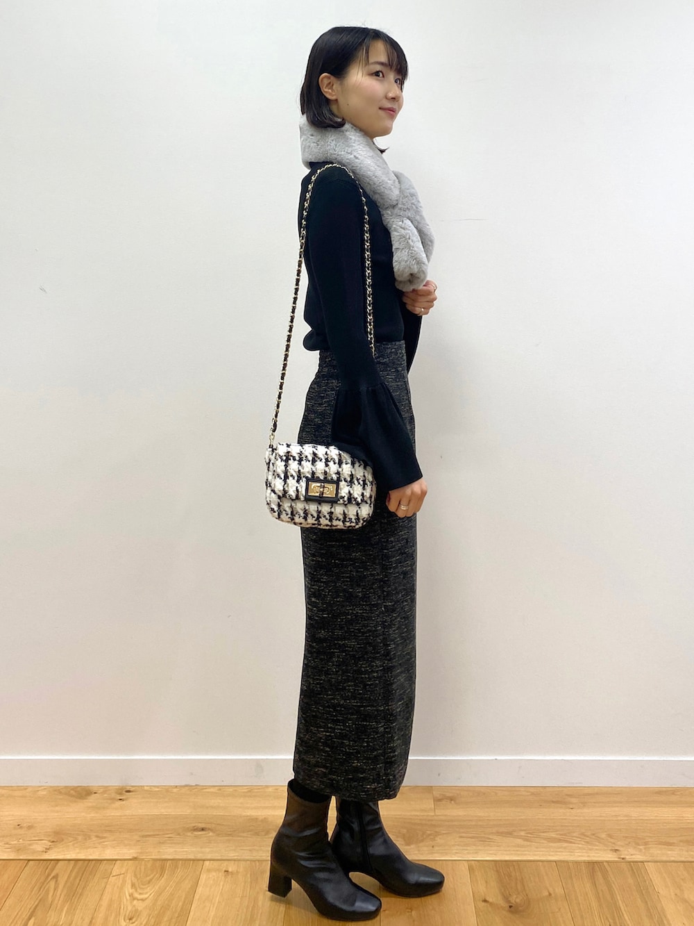 ブラック系のニット/セーター、ブラック系のブーツ、ブラック系のショルダーバッグを着用したレディースの冬コーディネートの2枚目の写真