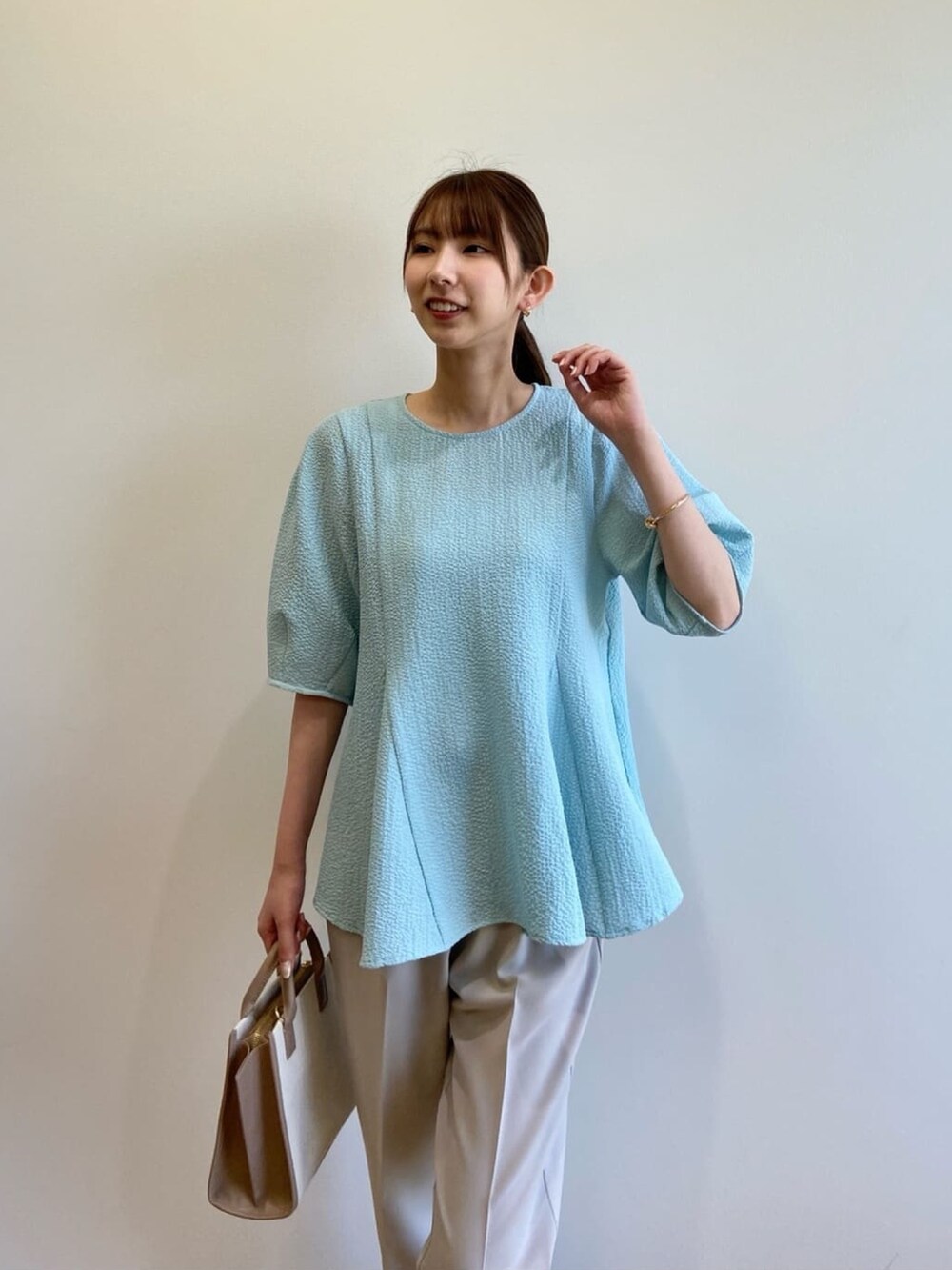 ブルー系のシャツ/ブラウス、ベージュ系のハンドバッグ、グレー系のその他パンツを着用したレディースの春コーディネートの5枚目の写真