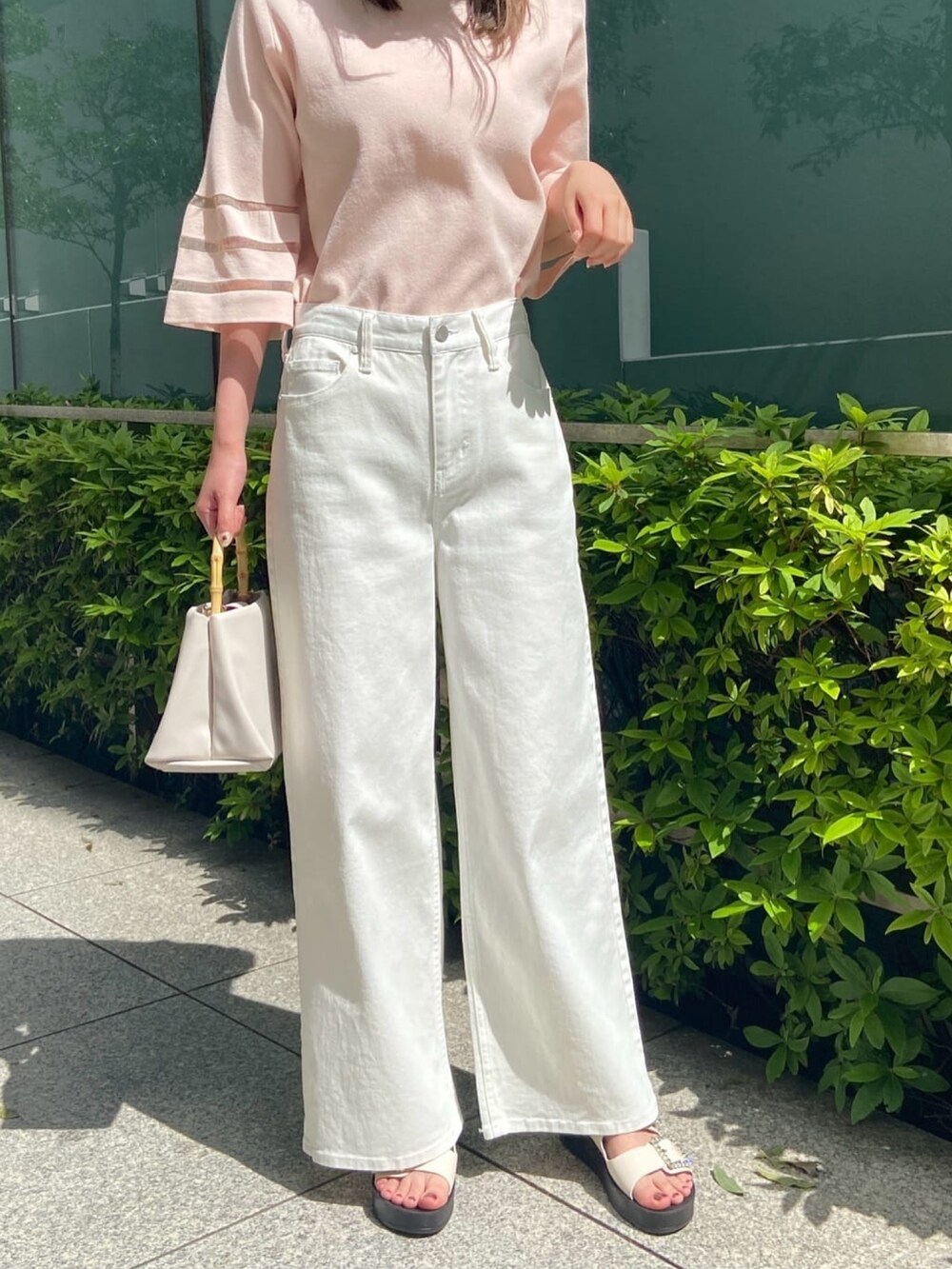 ピンク系のニット/セーター、ホワイト系のデニムパンツ、ホワイト系のサンダルを着用したレディースの春コーディネートの9枚目の写真