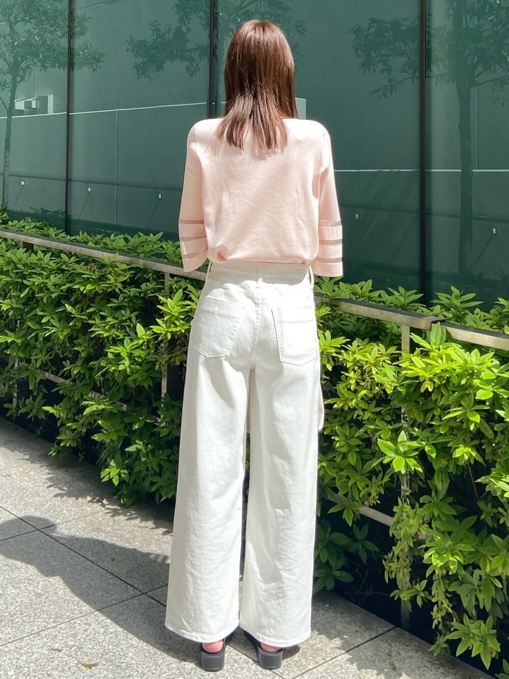 ピンク系のニット/セーター、ホワイト系のデニムパンツ、ホワイト系のサンダルを着用したレディースの春コーディネートの6枚目の写真