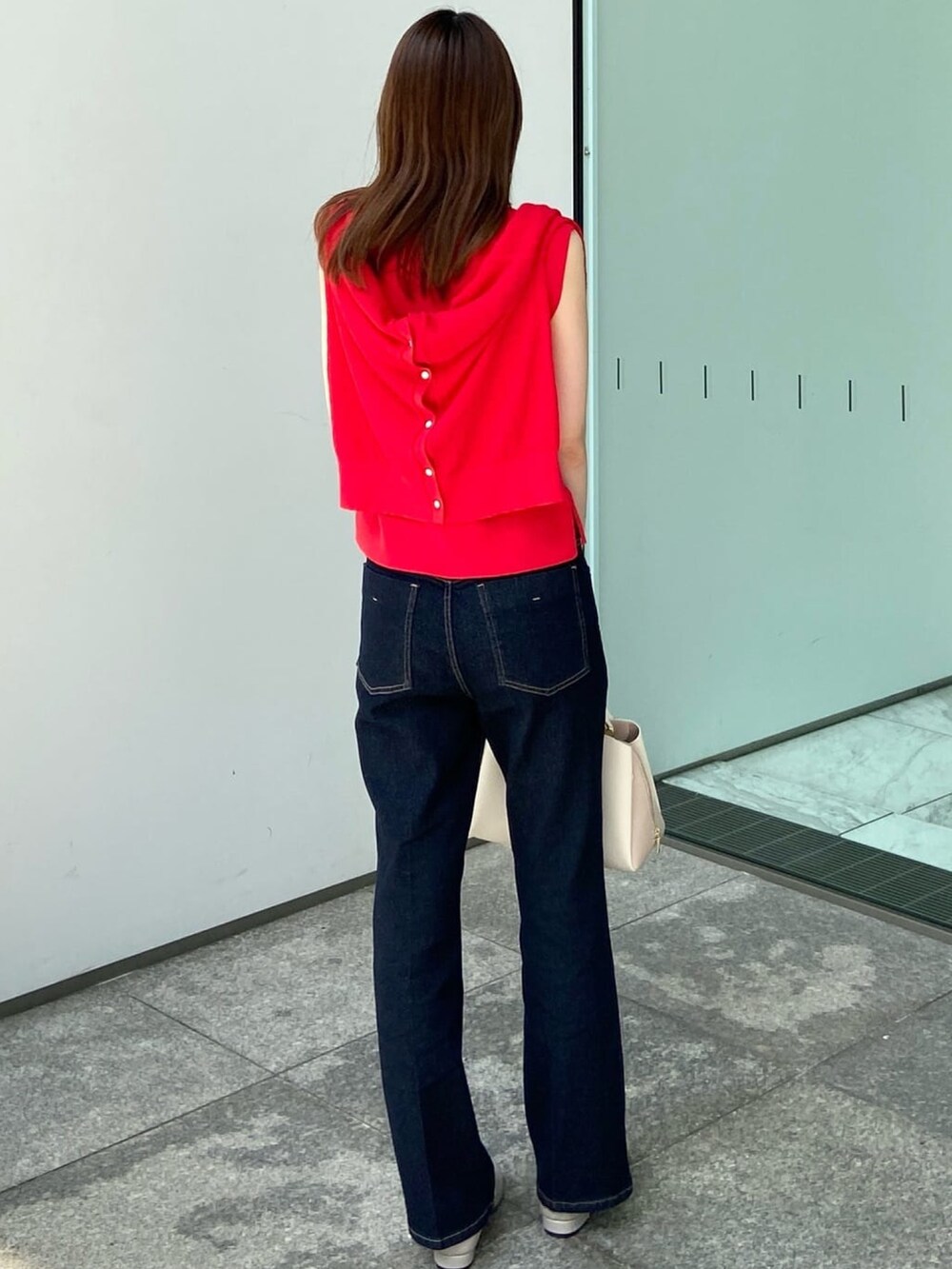 レッド系のカーディガン/ボレロ、レッド系のニット/セーター、ブルー系のデニムパンツを着用したレディースの夏コーディネートの4枚目の写真