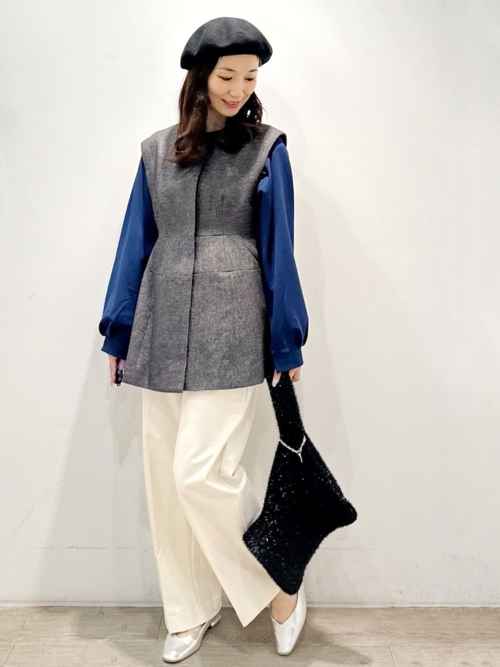 ブラック系のハンドバッグ、ホワイト系のその他パンツ、グレー系のベストを着用したレディースの秋コーディネートの3枚目の写真