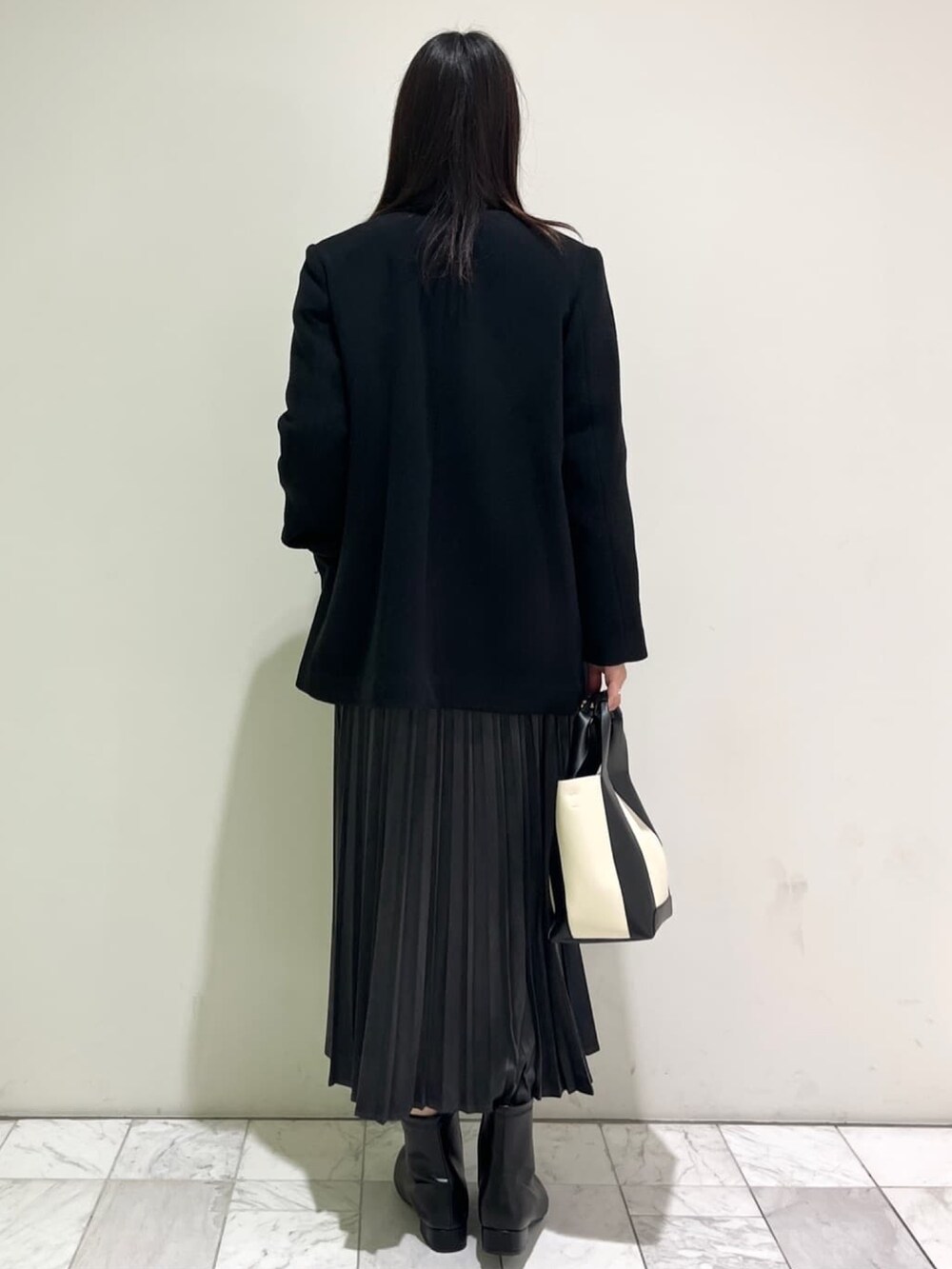 ブラック系のブーツ、ブラック系のTシャツ/カットソー、ブラック系のノーカラーコートを着用したレディースの秋コーディネートの3枚目の写真