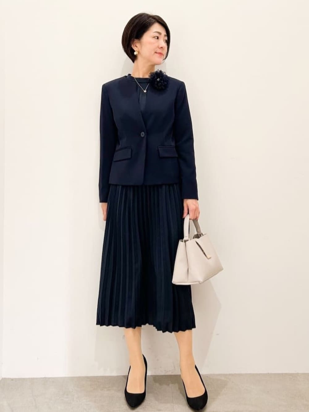 ブルー系のノーカラージャケット、ブルー系のワンピース、ブラック系のパンプスを着用したレディースの冬コーディネートの2枚目の写真