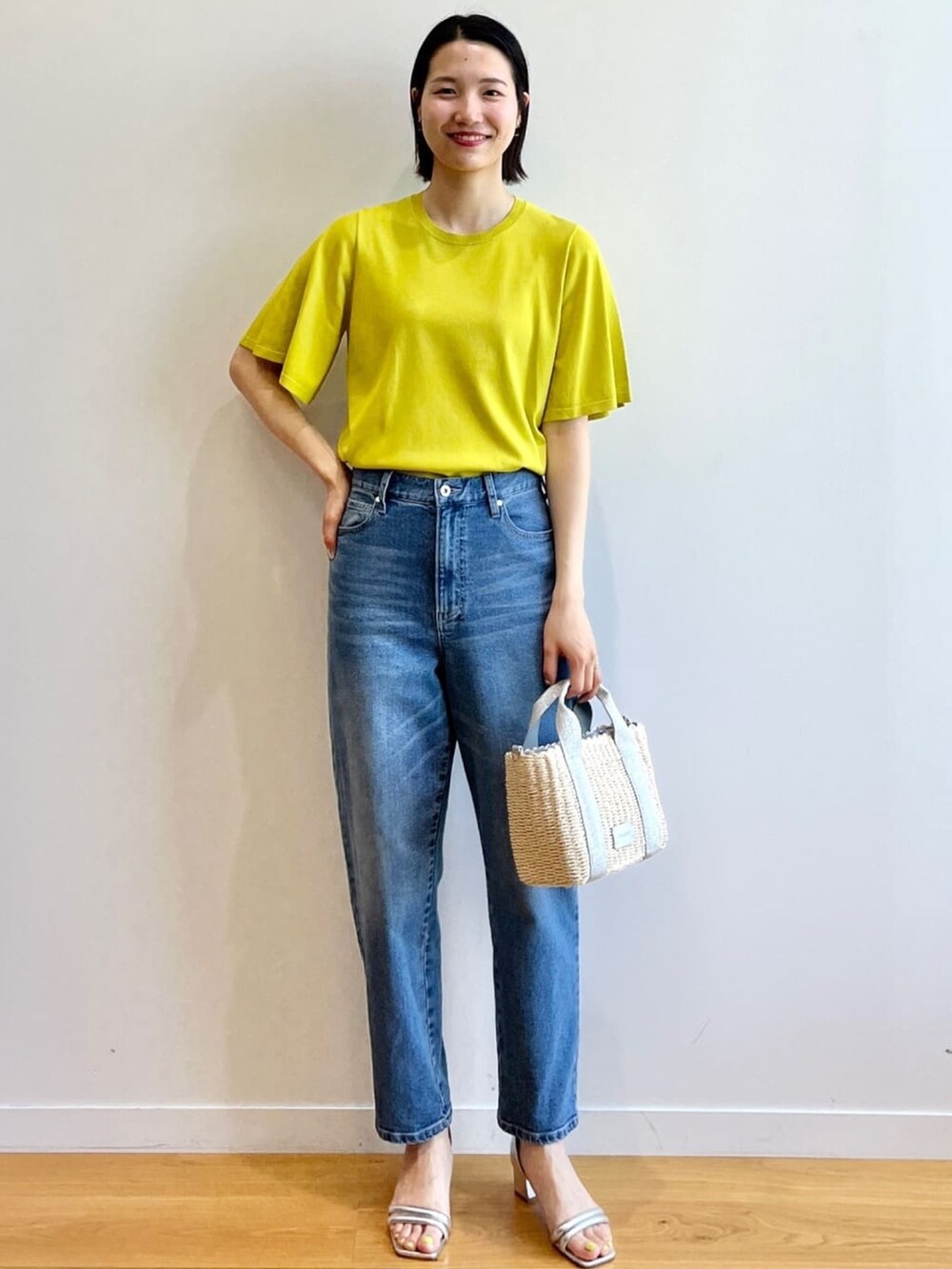 グリーン系のニット/セーター、ブルー系のデニムパンツ、シルバー系のショルダーバッグを着用したレディースの夏コーディネートの2枚目の写真