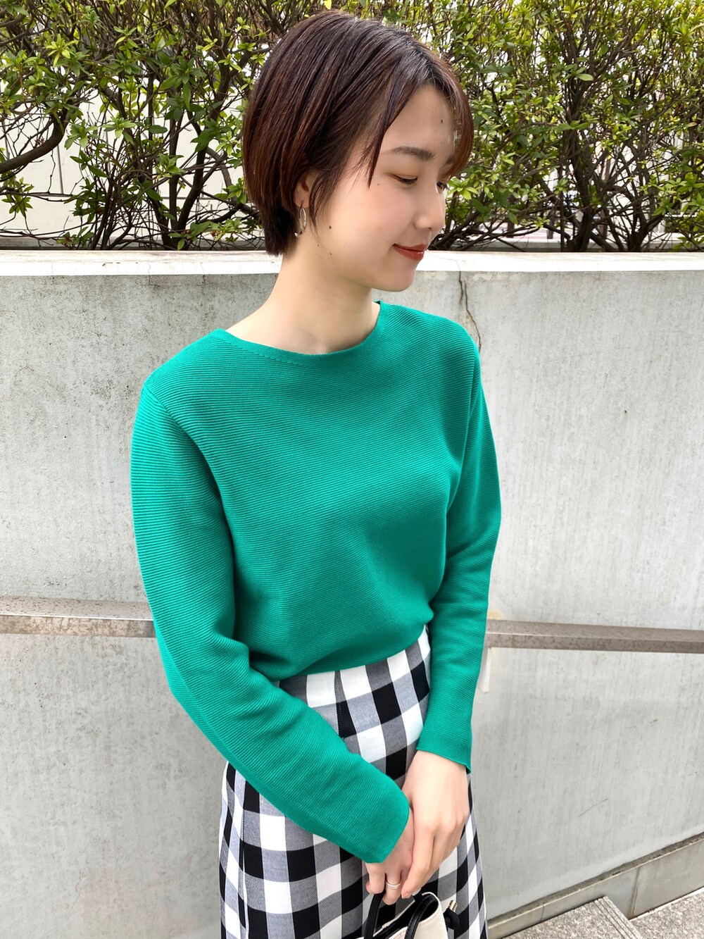 グリーン系のニット/セーター、ブラック系のスカート、ベージュ系のサンダルを着用したレディースの春コーディネートの2枚目の写真