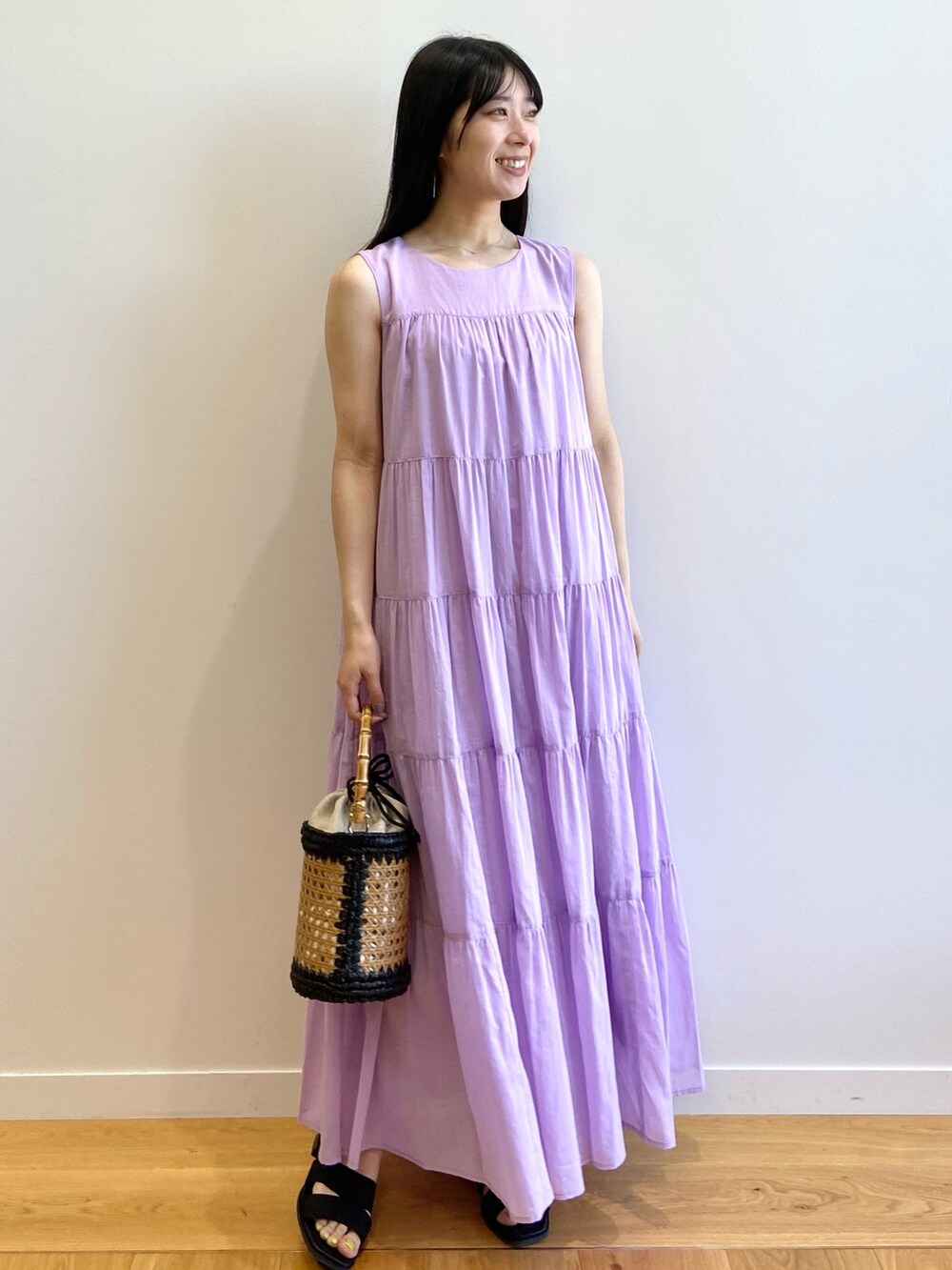 パープル系のワンピース、ブラック系のトートバッグ、ブラック系のサンダルを着用したレディースの夏コーディネートの2枚目の写真