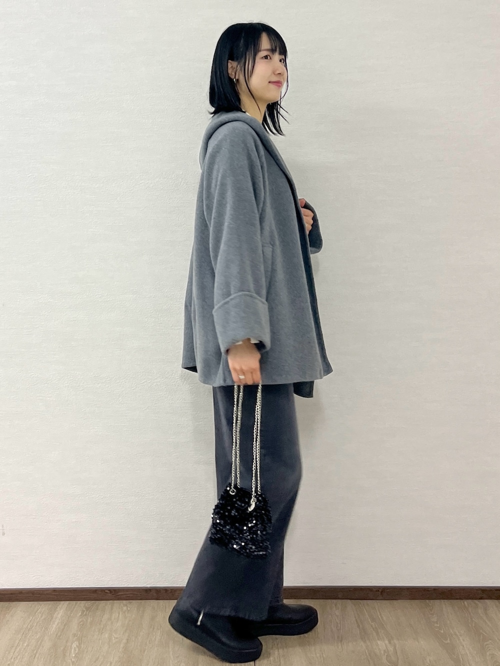 ホワイト系のニット/セーター、グレー系のその他アウター、ブラック系のショルダーバッグを着用したレディースの冬コーディネートの5枚目の写真