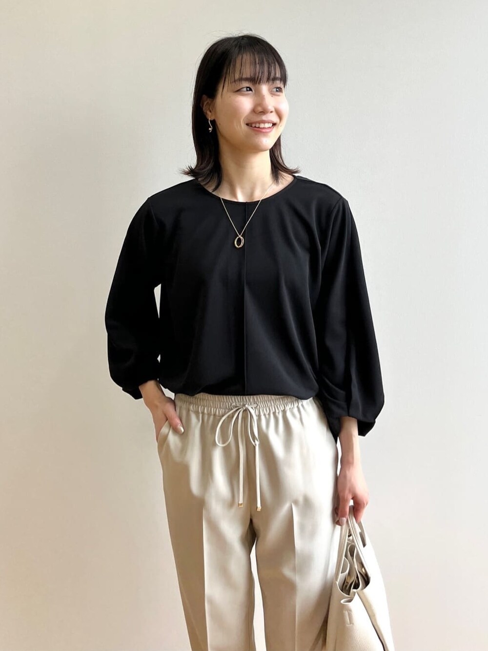 ブラック系のTシャツ/カットソー、ベージュ系のその他パンツ、ブラック系のサンダルを着用したレディースの春コーディネートの3枚目の写真