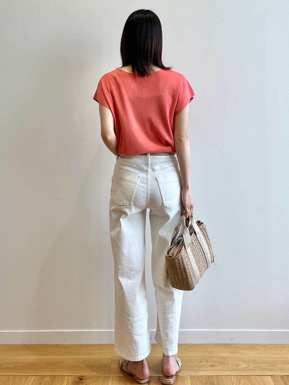 オレンジ系のニット/セーター、ホワイト系のデニムパンツ、ベージュ系のトートバッグを着用したレディースの春コーディネートの3枚目の写真