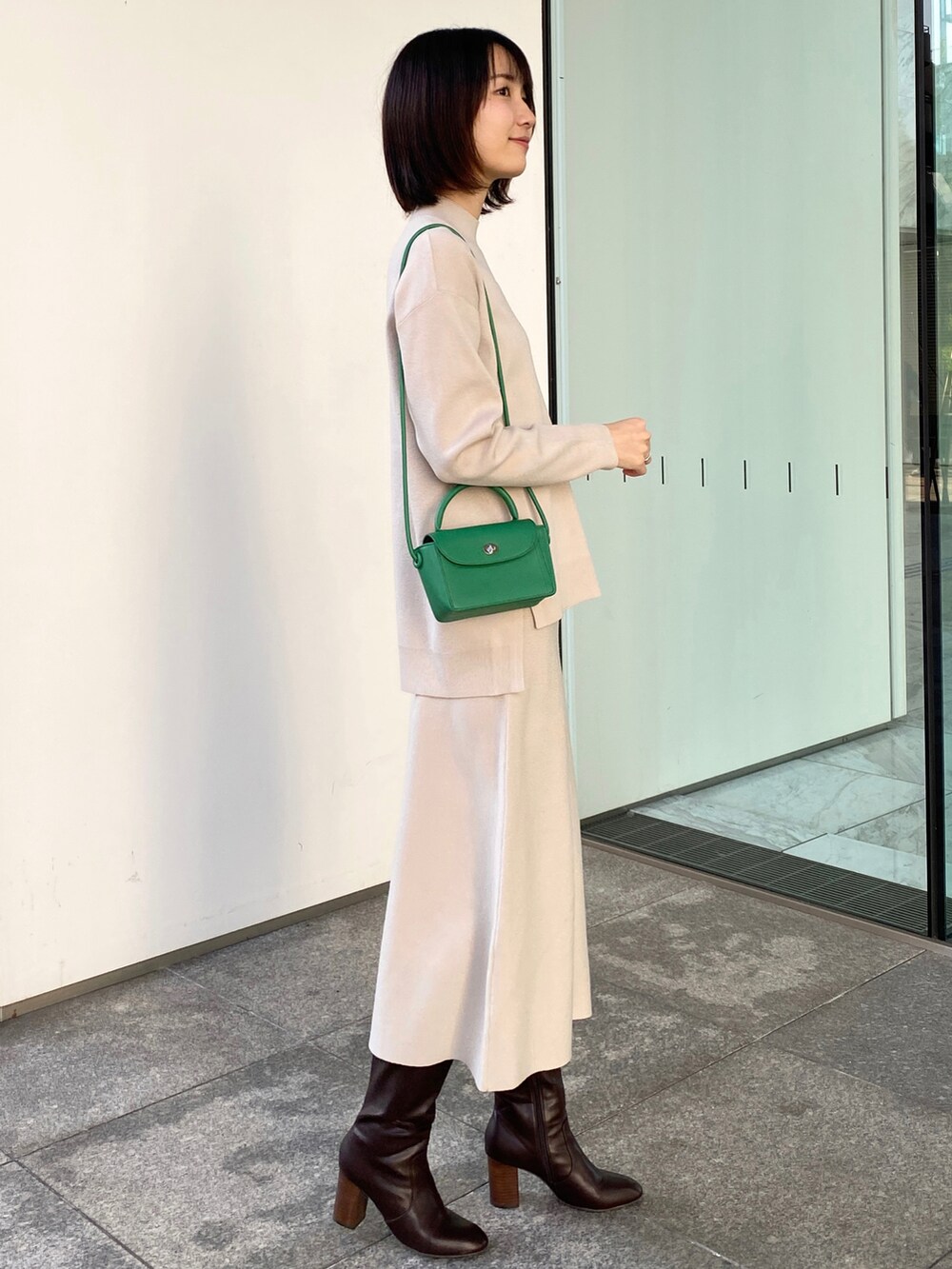 ホワイト系のブルゾン、ベージュ系のニット/セーター、グリーン系のショルダーバッグを着用したレディースの冬コーディネートの4枚目の写真