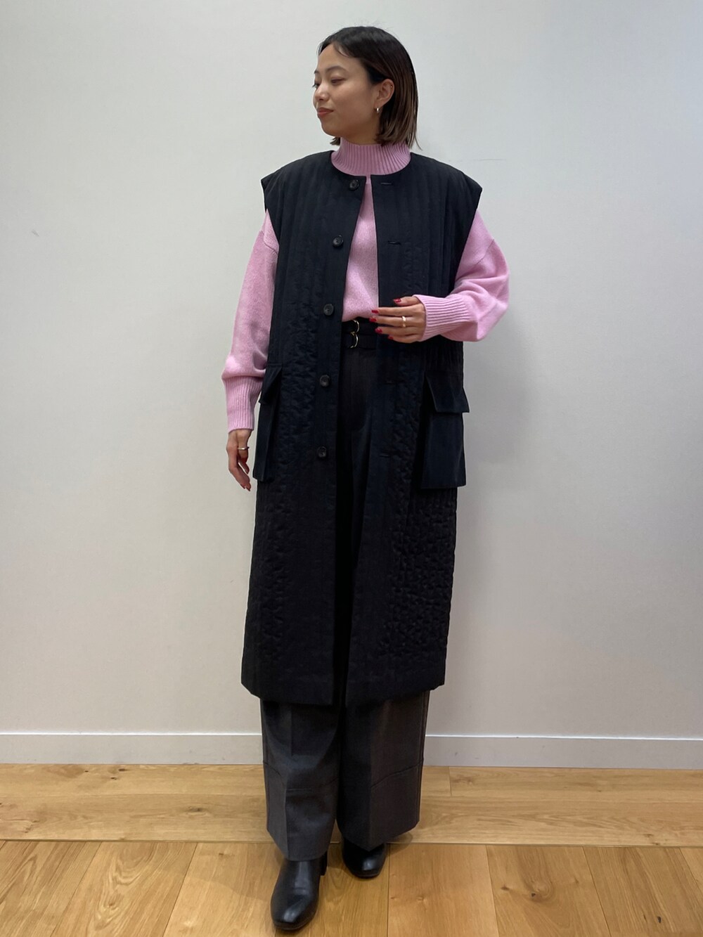 ブラック系のトレンチコート、ピンク系のニット/セーター、ブラック系のブーツを着用したレディースの秋コーディネートの3枚目の写真