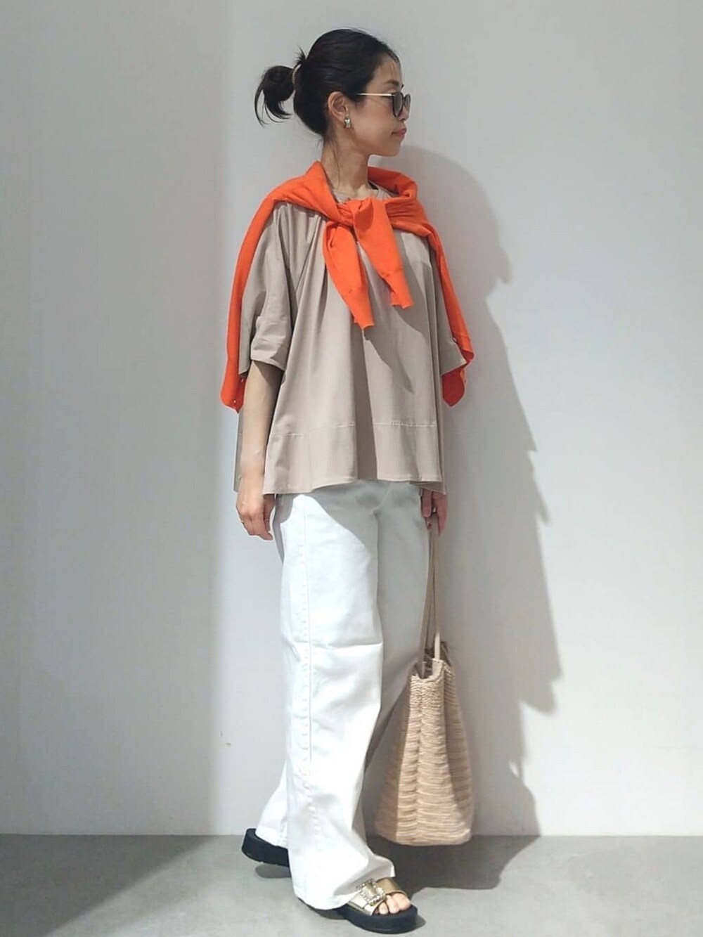 ベージュ系のTシャツ/カットソー、オレンジ系のカーディガン/ボレロ、ホワイト系のデニムパンツを着用したレディースの春コーディネートの4枚目の写真