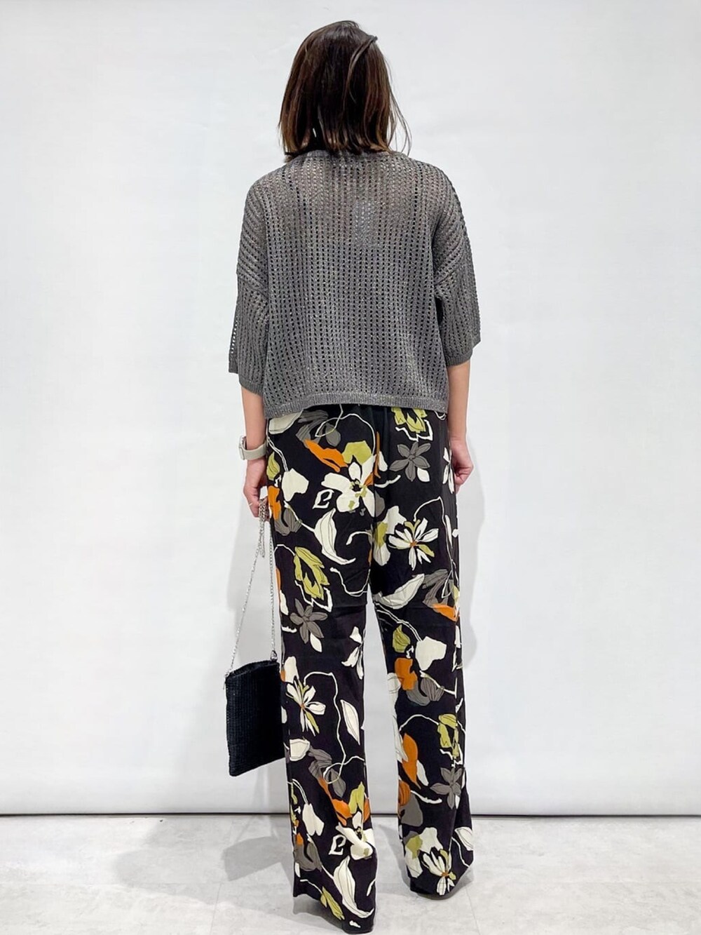 シルバー系のニット/セーター、ブラウン系のその他パンツ、ブラック系のショルダーバッグを着用したレディースの夏コーディネートの6枚目の写真