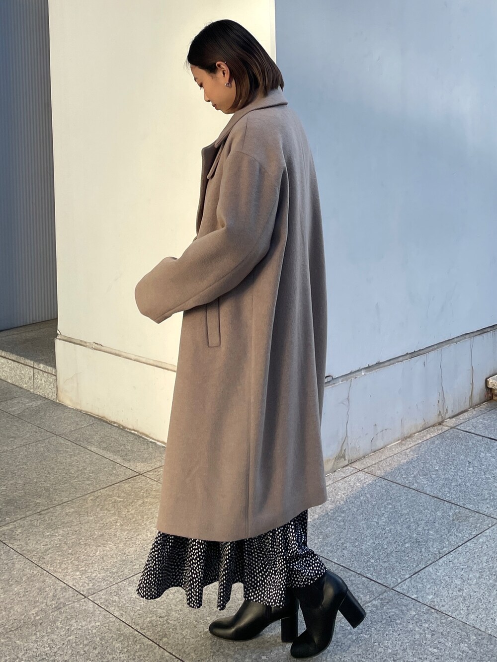 ベージュ系のチェスターコート、ベージュ系のニット/セーター、ブラック系のブーツを着用したレディースの冬コーディネートの2枚目の写真