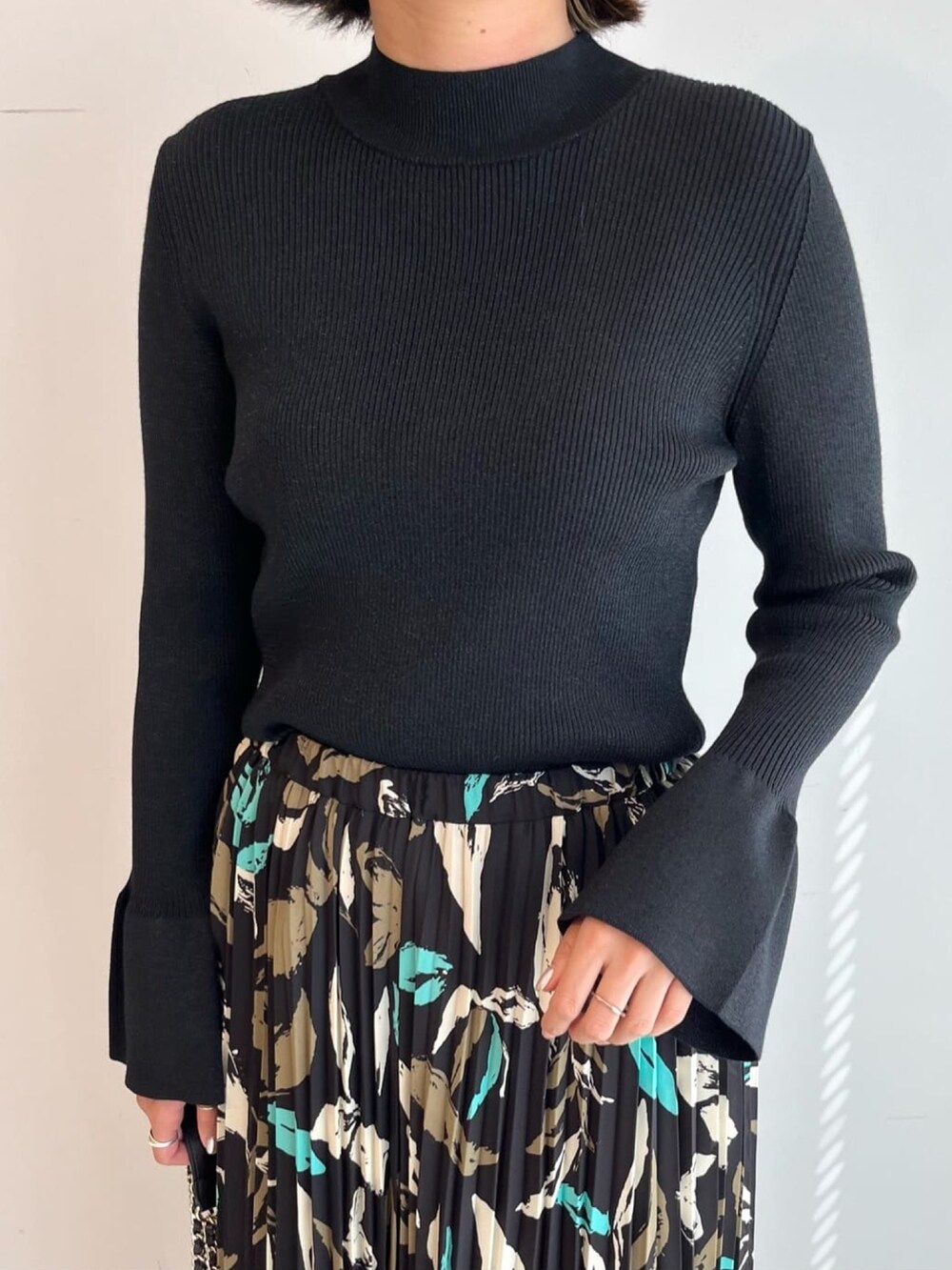 ブラック系のニット/セーター、ブラック系のスカート、ブラック系のショルダーバッグを着用したレディースの秋コーディネートの3枚目の写真