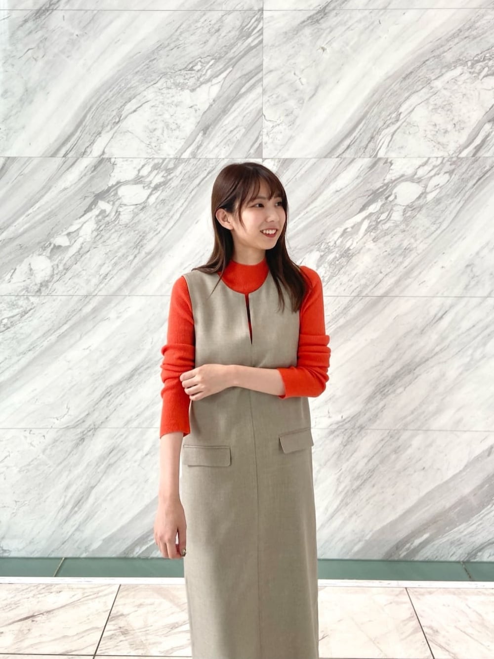 オレンジ系のニット/セーター、ベージュ系のワンピース、ホワイト系のブーツを着用したレディースの秋コーディネートの8枚目の写真