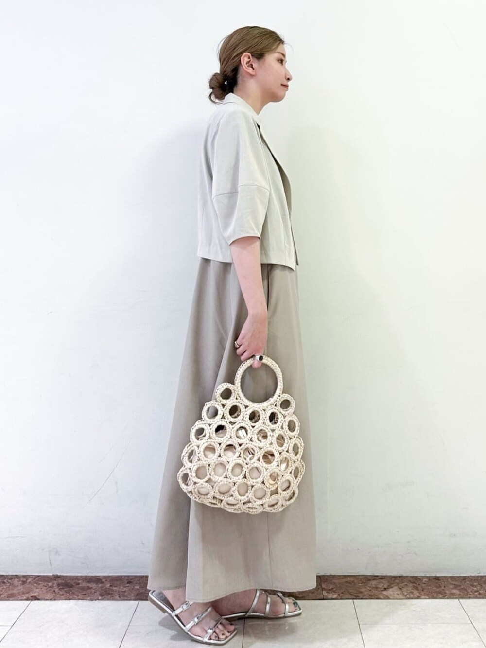 ベージュ系のテーラードジャケット、ベージュ系のワンピース、シルバー系のサンダルを着用したレディースの夏コーディネートの2枚目の写真