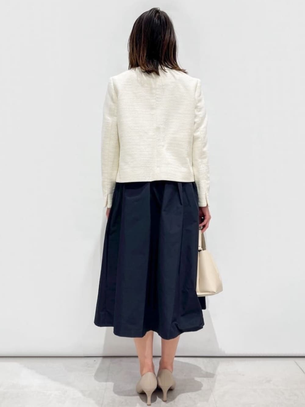 ブルー系のスカート、ホワイト系のノーカラージャケット、ホワイト系のシャツ/ブラウスを着用したレディースの冬コーディネートの3枚目の写真