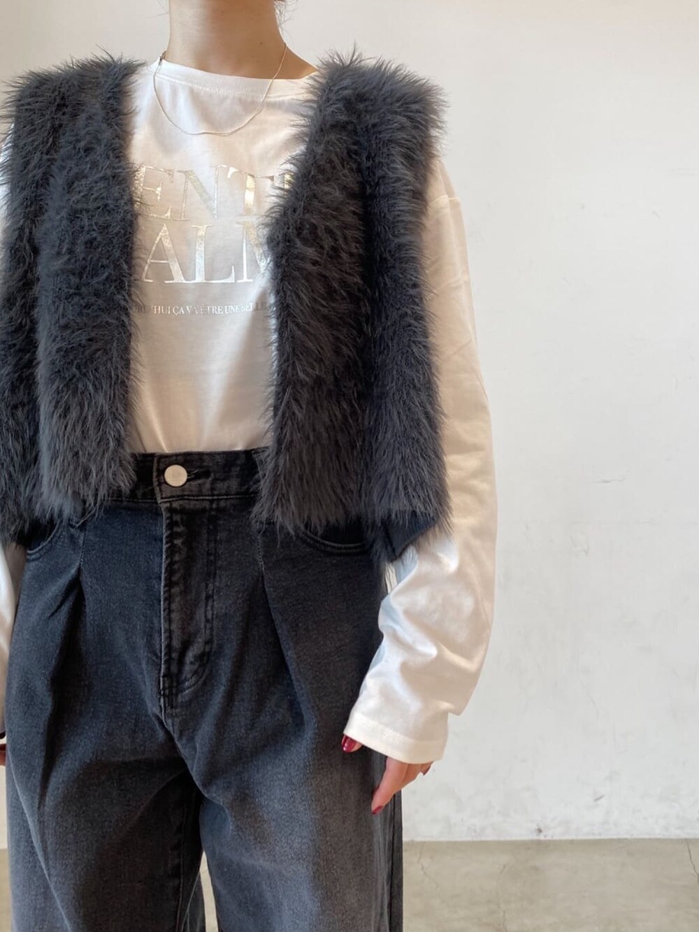 ホワイト系のTシャツ/カットソー、グレー系のベスト、ブラック系のデニムパンツを着用したレディースの秋コーディネートの4枚目の写真