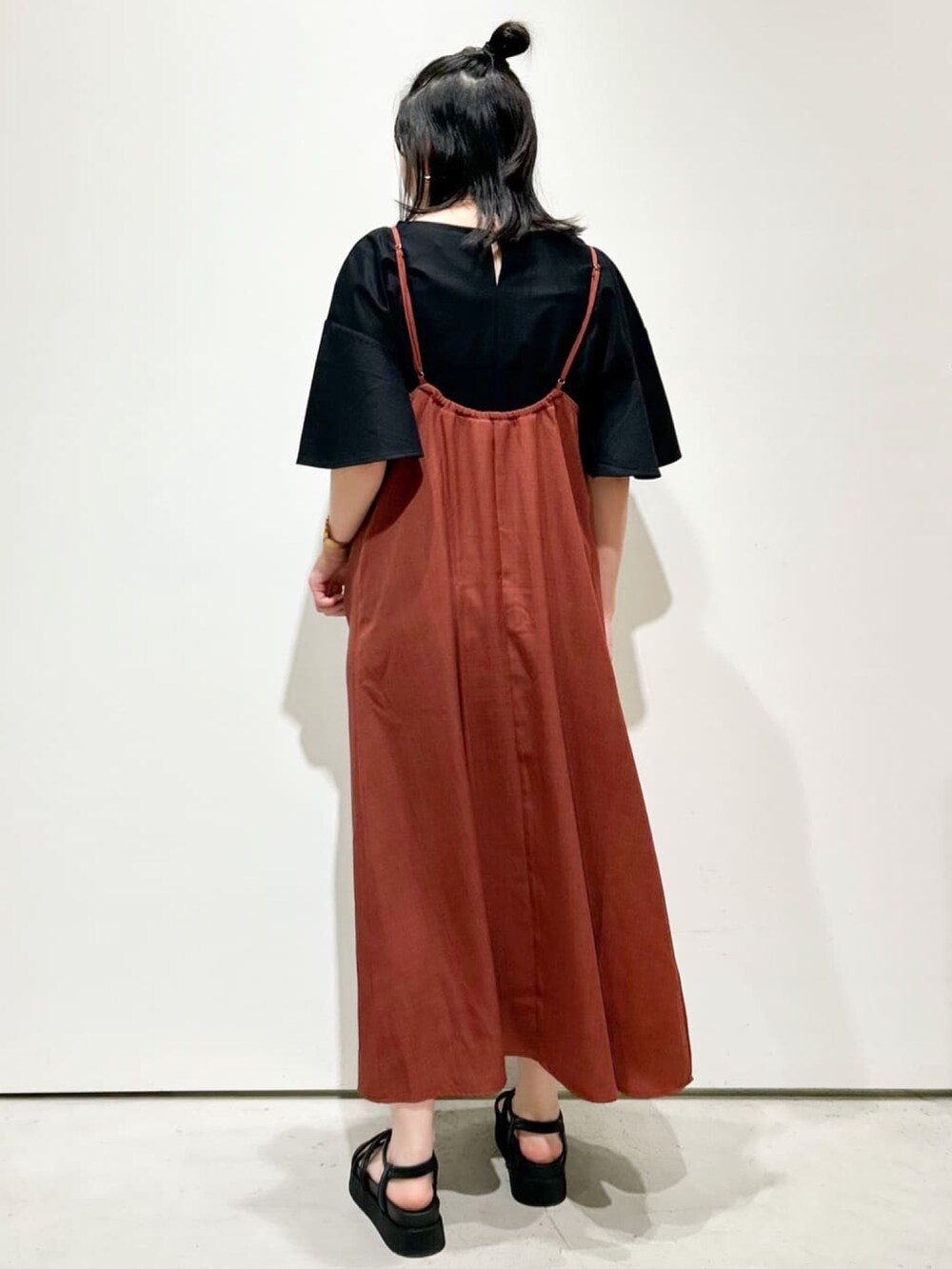 オレンジ系のワンピース、ブラック系のTシャツ/カットソー、ブラック系のサンダルを着用したレディースの夏コーディネートの3枚目の写真