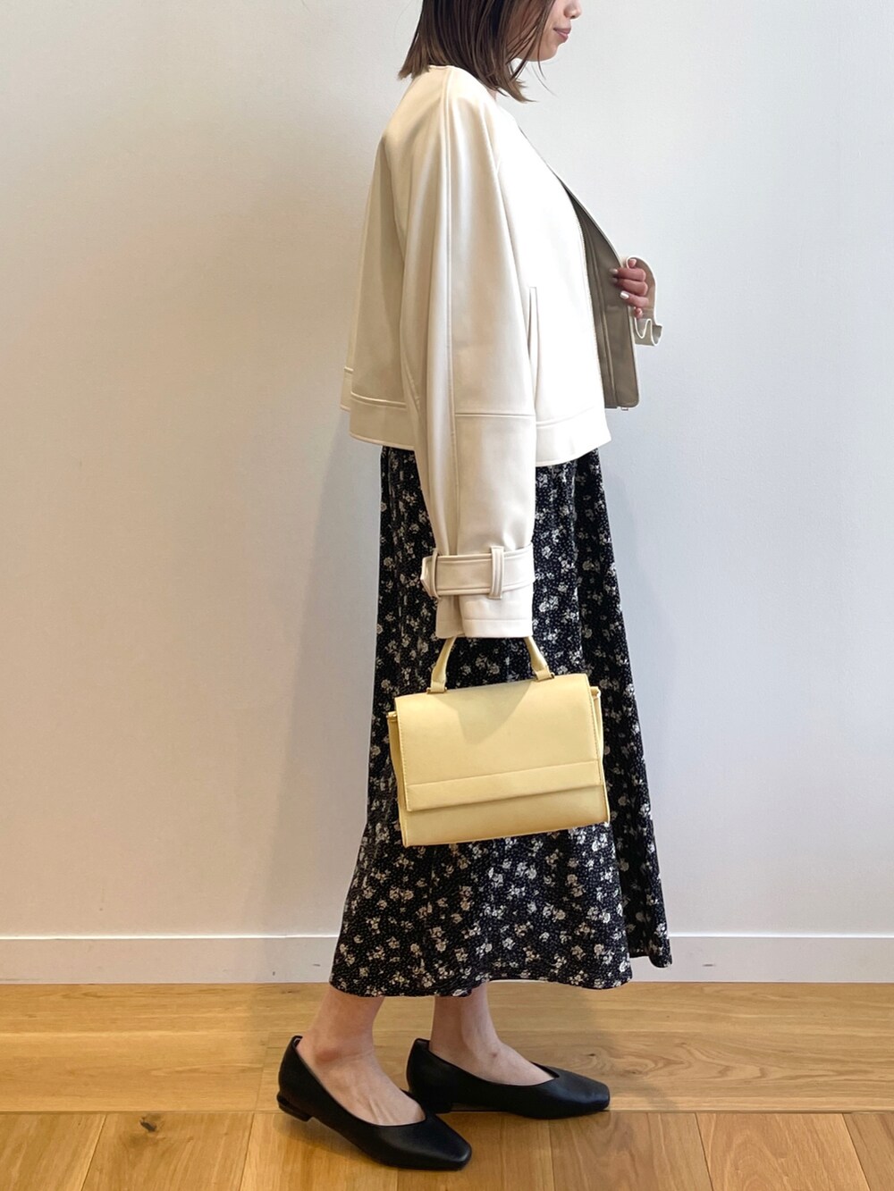 ベージュ系のノーカラージャケット、ブラック系のワンピース、イエロー系のショルダーバッグを着用したレディースの春コーディネートの2枚目の写真