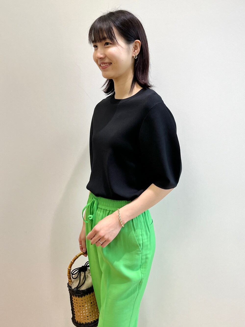 ブラック系のニット/セーター、ゴールド系のサンダル、ブラック系のトートバッグを着用したレディースの春コーディネートの5枚目の写真